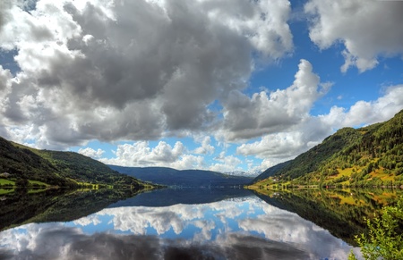 Beautiful norwegian lake with reflection of dramatic sky, scandinavian Europe.の写真素材