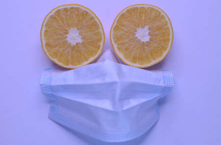 on the photo a face made of orange slices in a mask against covid on a white backgroundの写真素材
