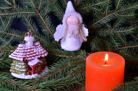 Christmas toys and a candle on the background of fir branchesの写真素材