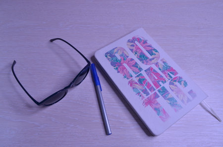 sunglasses, ballpoint pen and notebook on light background