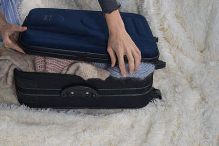 young woman is collecting a suitcase. The traveler preparing for journey, personal perspective...