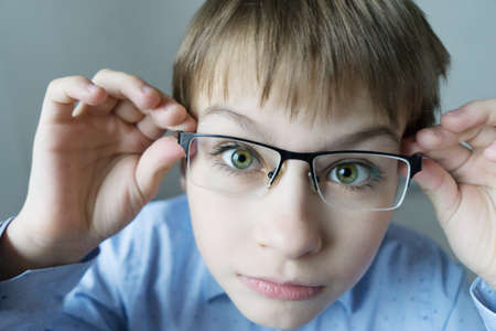 a 9-year-old boy in a blue shirt with glasses checks his eyesight. You should wear glasses. Eye health careの写真素材
