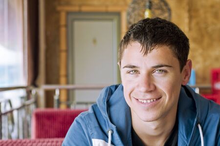 Young smiling man sitting in a cafeの写真素材