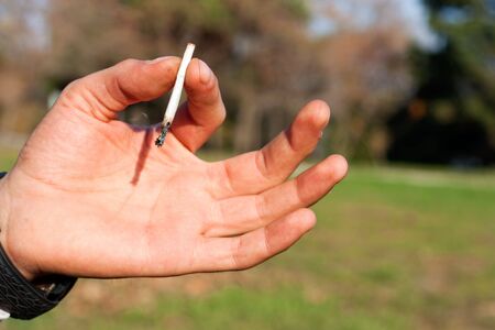 Hand with dirty fingers holding a marijuana cigaretteの写真素材