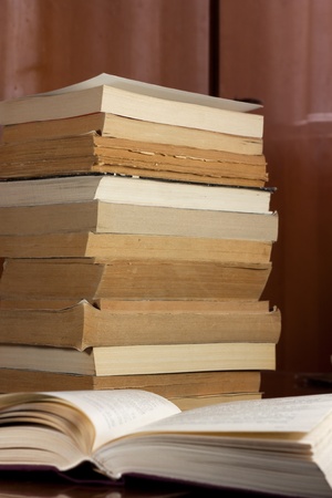 An opened book in front of old,gold edged booksの写真素材