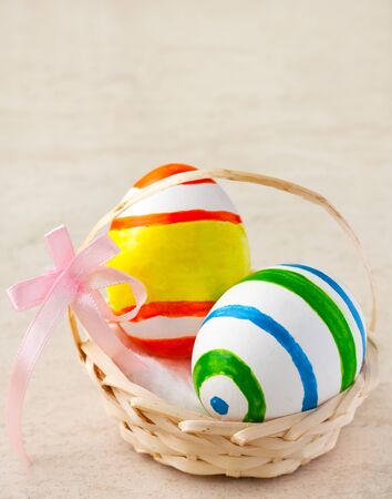 Painted easter eggs in a basket with ribbonの写真素材