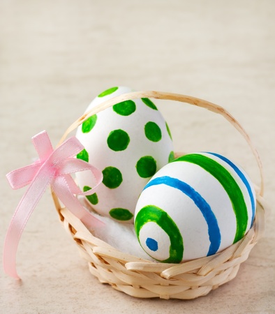 Painted easter eggs in a basket with ribbonの写真素材