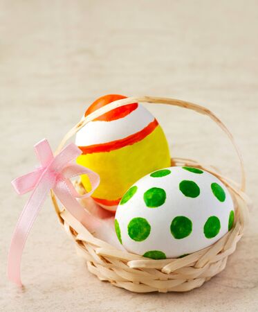 Painted easter eggs in a basket with ribbonの写真素材