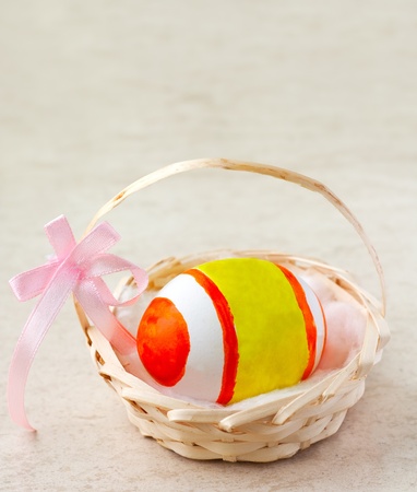 Painted easter egg in a basket with ribbonの写真素材
