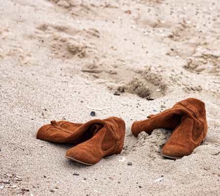 Woman boots abandoned on sandy beachの写真素材