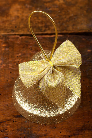 Cristmas decoration.Golden Christmas bell on wooden backgroundの写真素材