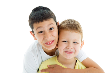 Two happy joyful and loving  brothers isolated on white background.Smilling at camera.Four years and nine years oldの写真素材
