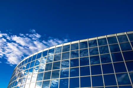Detail of modern building with glass windows and blue sky reflectionの写真素材