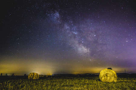 Serenity in summer time. Milkyway and stars above hay bales in field.の写真素材