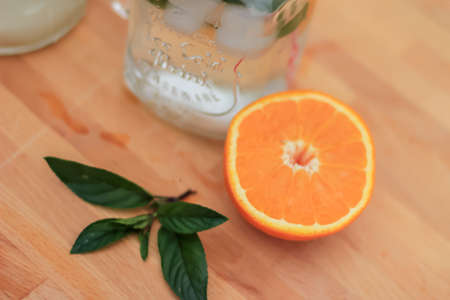 Fresh aromatic orange and mint water in glass jar served on a wooden table. topviewの写真素材