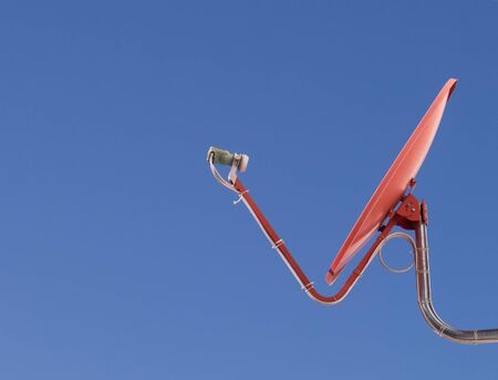 red TV satellite dish in a blue sky backgroundの写真素材