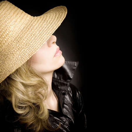 Portrait of the young woman in a hat on a black backgroundの写真素材