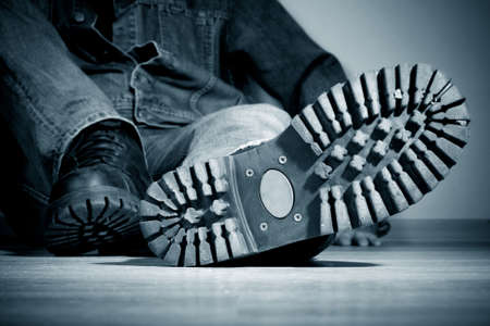 The young man sits on a floor. In the foreground a boot protectorの写真素材