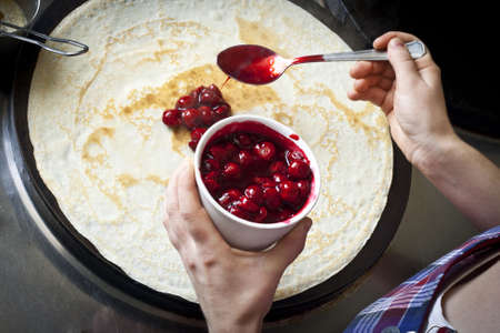 Making pancakes. The cook puts cherry jamの写真素材
