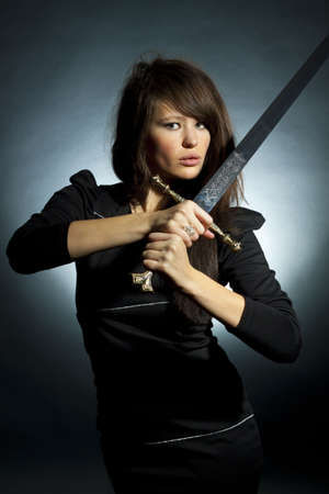 The beautiful young woman holds a sword in a handの写真素材