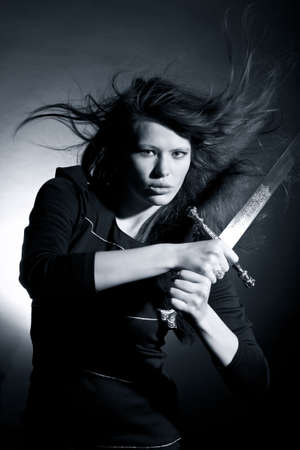 The beautiful young woman holds a sword in a handの写真素材