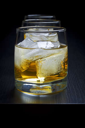 Whisky with ice in glasses on a black backgroundの写真素材