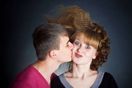The guy kisses the young woman. The young woman playfully was surprisedの写真素材