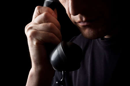 The man speaks by phone. A close up. A black backgroundの写真素材