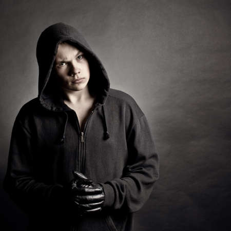 Portrait of the young man in a hood against a dark backgroundの写真素材