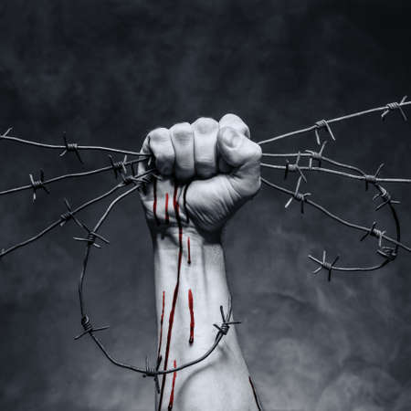 Rusty barbed wire in a strong man's handの写真素材