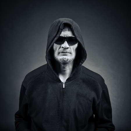 man in sunglasses and a hood on a dark background