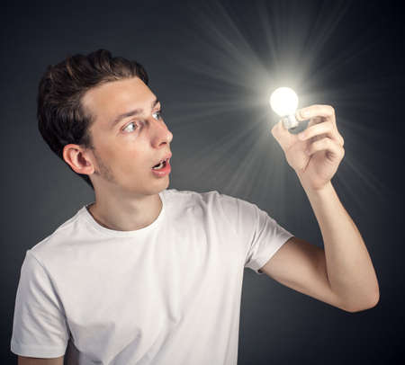 Young man holding a lighted lightbulbの写真素材
