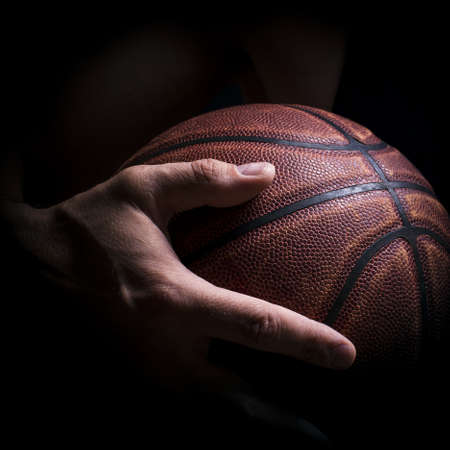 Fragment of a basketball ball in a hand of the basketball playerの写真素材