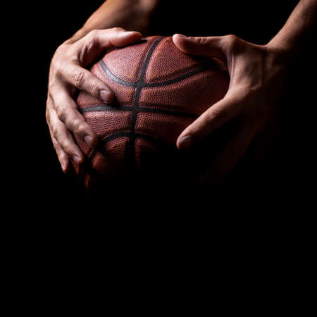 Basketball in the hands of the athlete isolated on white 