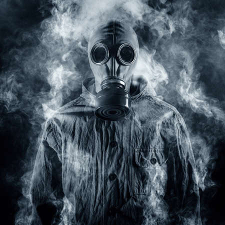 A man in a gas mask shrouded in smoke
