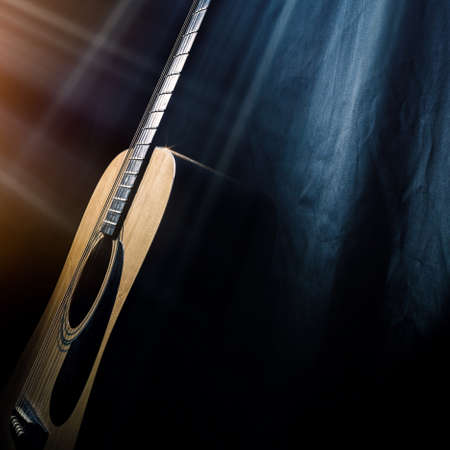 acoustic guitar on a black background in the rays of lightの写真素材