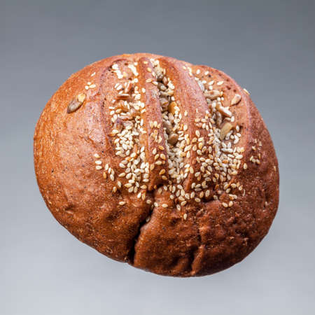 Bun with seeds on a gray background