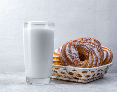 Appetizing custard rings and a glass of milk on a white background