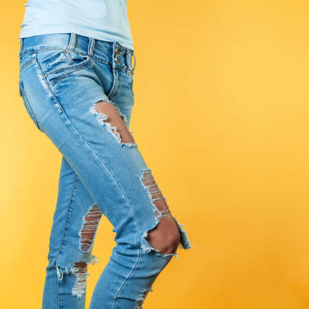 Female legs in torn jeans on an orange backgroundの写真素材