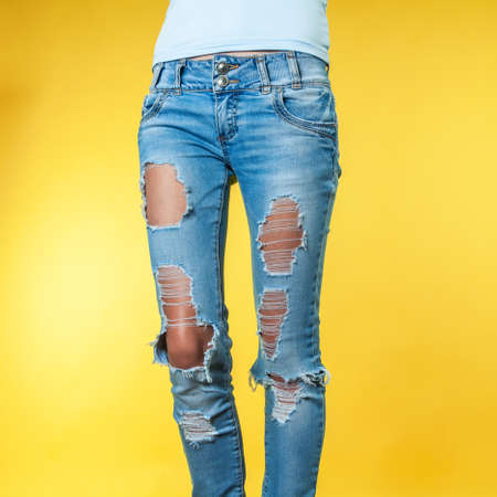Female legs in torn jeans on an orange backgroundの写真素材