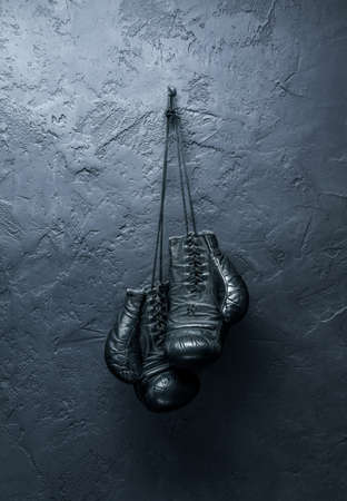 old boxing gloves hang on nail on textured wallの写真素材