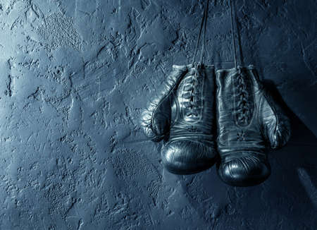 old boxing gloves hang on nail on textured wallの写真素材