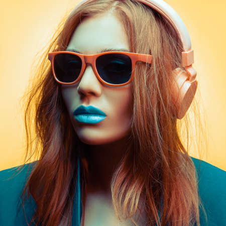 Pretty girl in sunglasses and headphones listens to music. The image is colored.の写真素材