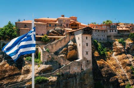 Greek flag in front of The Holy Monastery of Great Meteoron in Meteora - complex of Orthodox monasteries on mountains, Thessaly, Greeceの写真素材