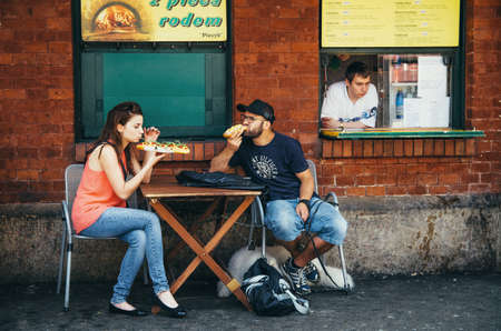 KRAKOW, POLAND - JUNE 26, 2015: The couple eat traditional polish fastfood zapekanka in Nowy Squareのeditorial素材