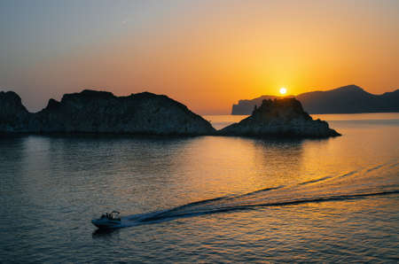 The boat yacht sails near Santa Ponsa coastline at sunset in Morro d'en Pere Joan bay in Mallorca, Balearic islands of Spain. Es Malgrat rocks.の写真素材