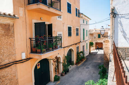 Alcudia, Mallorca, Spain - May 23, 2015: Adult walks through the narrow streets of historical town part of Alcudia with its traditional house and architectureの写真素材