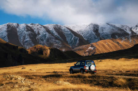Off-road travel on car on mountain road against rocks and glacier in Caucasus, Georgia. Beautiful lights and colors at sunsetの写真素材
