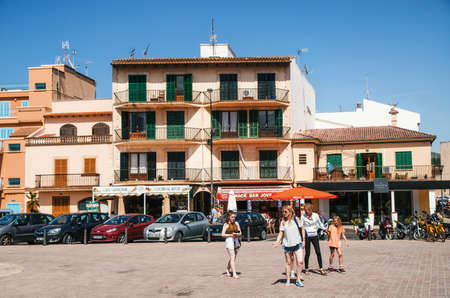 Alcudia, Mallorca, Spain - May 23, 2015: Family of tourists walking along at historical town part of Alcudia with its traditional house and cafe. Carles V square area.のeditorial素材
