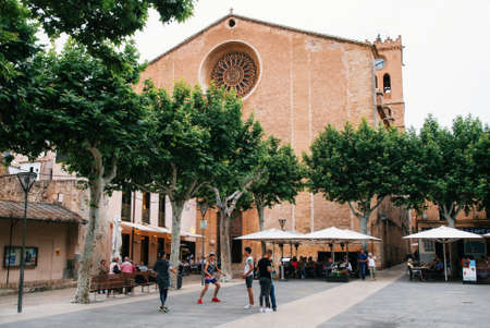 Pollensa, Mallorca, Spain: May 24, 2016: Young men play football against Church of Our Lady of the Angels on Main Square Plasa Major of Pollensaのeditorial素材